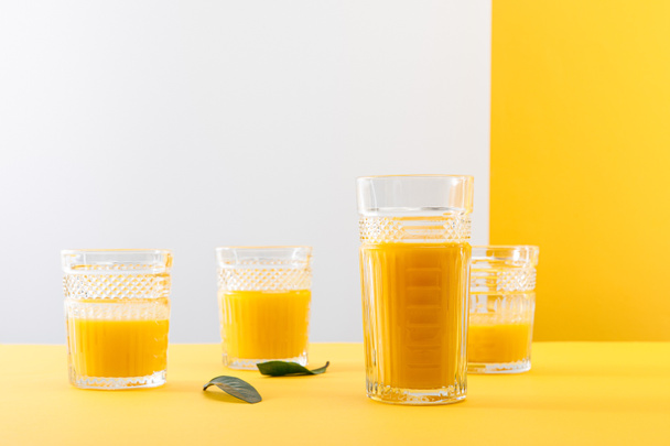 glasses of fresh delicious yellow smoothie near green leaves - Foto, imagen