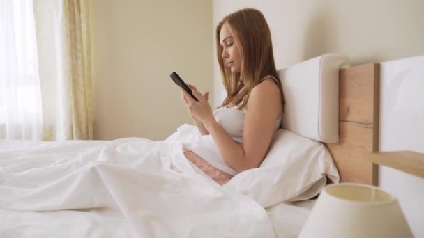 Girl using smartphone in bed. - Metraje, vídeo