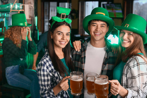 Young friends with beer celebrating St. Patrick's Day in pub - Photo, image