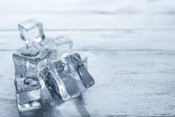 Crystal clear ice cubes with water drops on white wooden table, closeup. Space for text - Fotografie, Obrázek