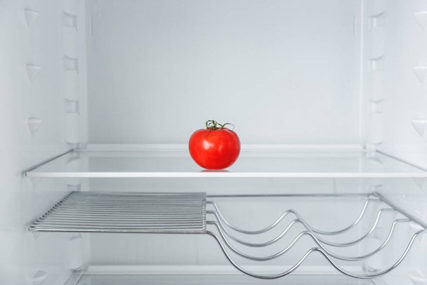 Fresh ripe tomato on empty shelf in refrigerator - Foto, imagen