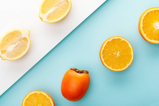 Vista dall'alto delle metà arancio e limone con cachi su sfondo blu e bianco
 - Foto, immagini