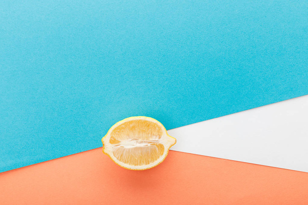 Top view of lemon half on blue, orange and white background - Foto, afbeelding