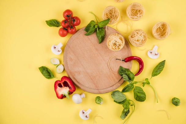 Pasta on a wooden board, vegetables. Top view. Copy space for text. - Fotoğraf, Görsel