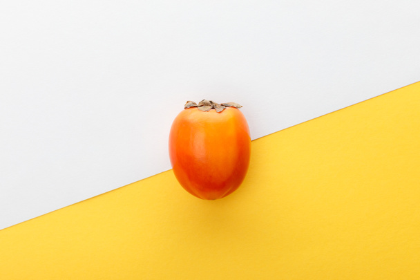 Top view of persimmon on white and yellow background - Fotoğraf, Görsel