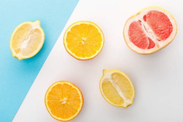 Top view of citrus halves on white and blue background - Fotoğraf, Görsel