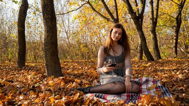 νεαρή όμορφη γυναίκα με ένα ποτήρι κρασί στο πάρκο το φθινόπωρο - Φωτογραφία, εικόνα