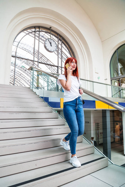 Girl goes down stairs and speaks on her smartphone - Foto, Bild