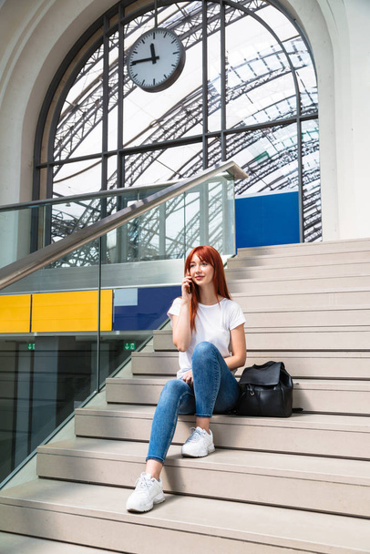 Girl sits on station on stairs talking on phone - Foto, Bild
