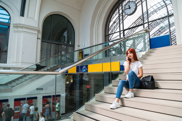 Girl sits on station on stairs talking on phone - Photo, Image