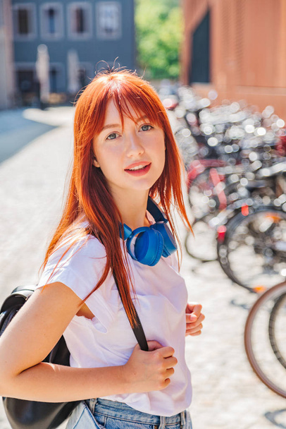 Cute redhead girl having fun on street near bikes - Foto, Imagen