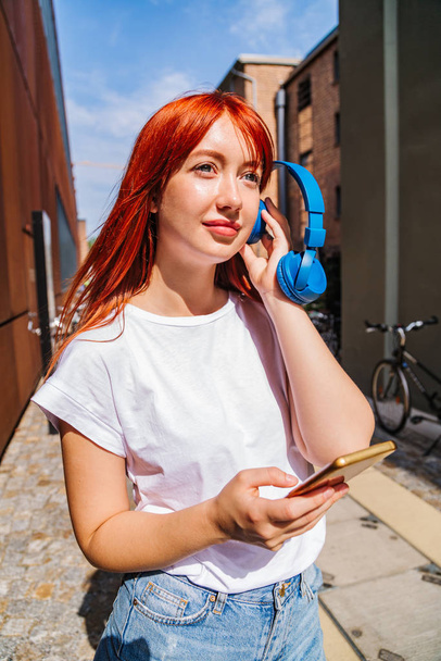 Girl listens to music putting headphones to ear - Photo, Image