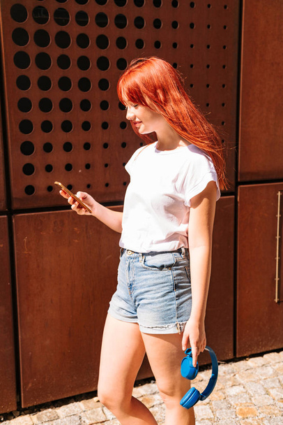 Redhead woman listening wireless music with headphones - Foto, immagini