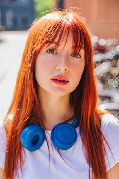Portrait of red-haired girl in city in sunlight - Zdjęcie, obraz