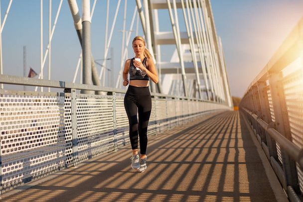 volwassen fitness vrouw joggen op brug. - Foto, afbeelding