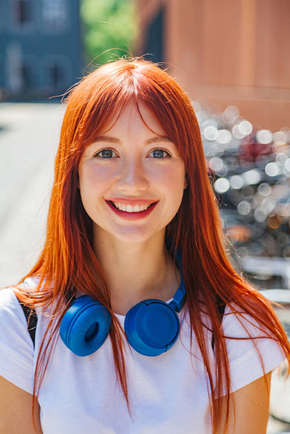 Portrait of red-haired girl in city in sunlight - Photo, Image