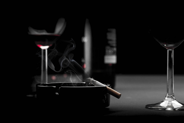 Sigaret, glas wijn en fles wijn  - Foto, afbeelding