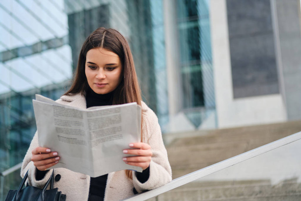 Bonita mulher de negócios elegante ler atenciosamente jornal no centro da cidade
 - Foto, Imagem