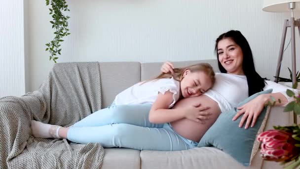 Young pregnant mother and her little daughter indoors. Child and her mom waiting for a little new born baby. Happy family expecting. - Footage, Video