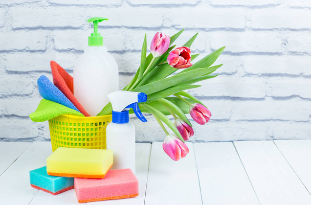 Frühjahrsputz-Urlaubskonzept, Vorräte und Werkzeuge zum Putzen und Frühlingsblumen. Flüssige Desinfektionsmittel, Schwämme und Reinigungstücher. Kopierraum - Foto, Bild