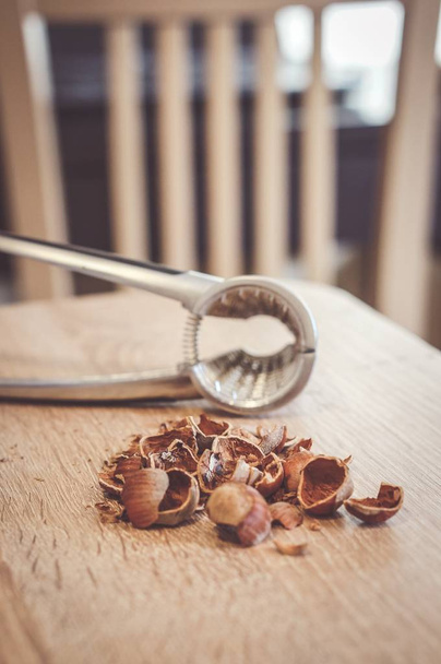 Soft focus shot of broken hazelnut nut shells on a table with a nutcracker - Fotó, kép