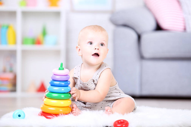 Beautiful little boy sitting and playing with plastic toys at ho - Foto, Bild