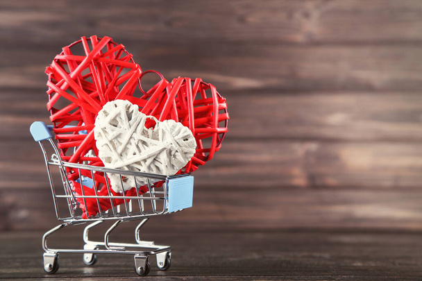 Colorful hearts with shopping cart on wooden table - Photo, Image