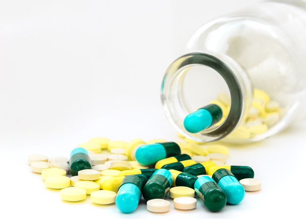 Пролитые капсулы и таблетки со стеклянной бутылкой
 - Фото, изображение