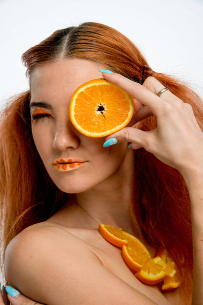 beautiful redhead girl with orange fruit  - Photo, Image