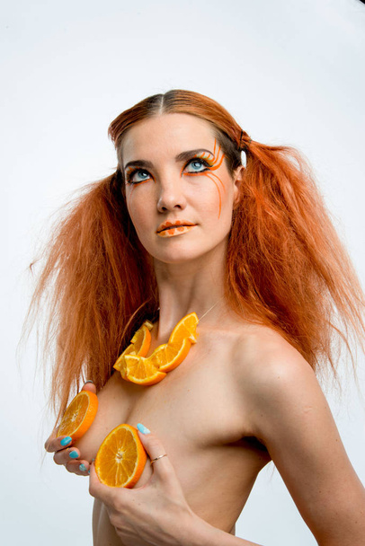 beautiful redhead girl with orange fruit  - Foto, imagen