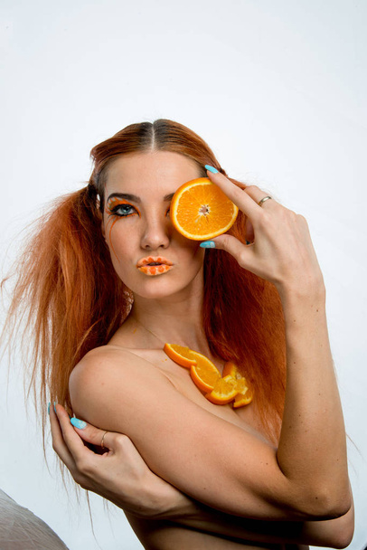 beautiful redhead girl with orange fruit  - Fotografie, Obrázek