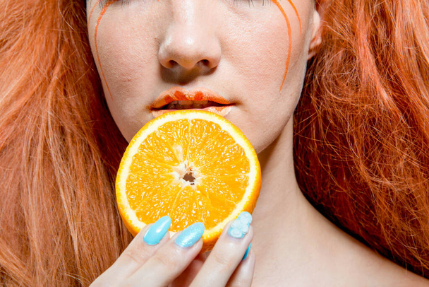 beautiful redhead girl with orange fruit  - 写真・画像
