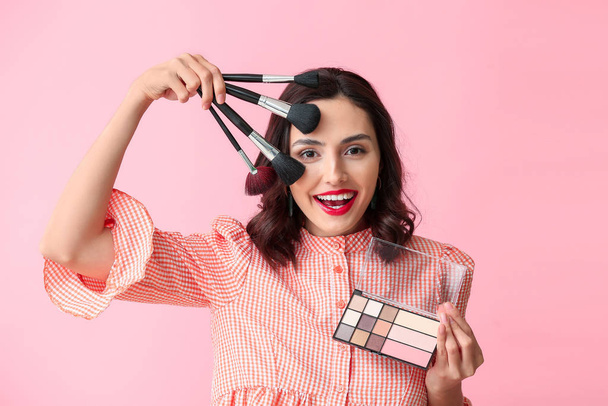 Beautiful young woman applying makeup on color background - Photo, image