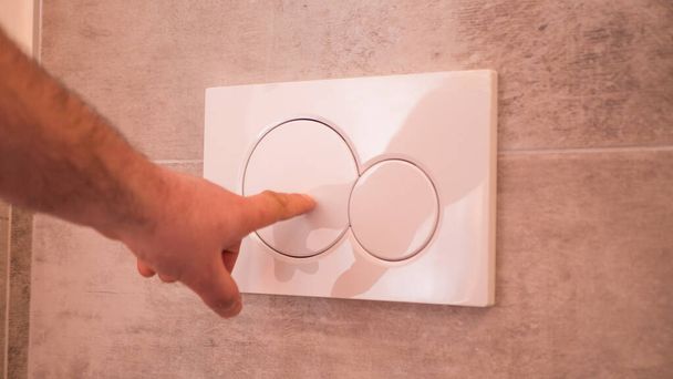 経済的なトイレは2つのボタンでプレスをフラッシュします。隠しトイレのシスタンの二重のメカニズムを使用して水をフラッシュします。近代的なバスルーム要素. - 写真・画像