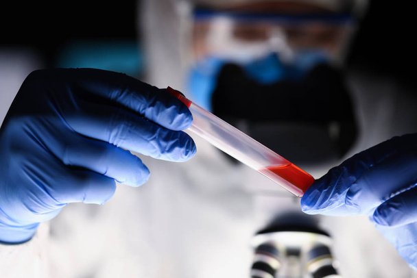 暗い研究室で血液サンプルを調べる男性化学者 - 写真・画像