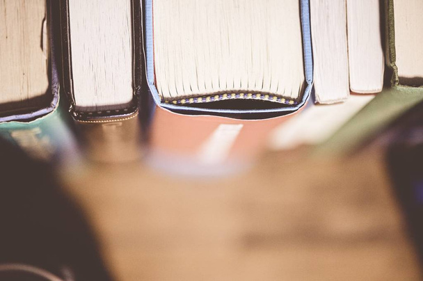 Closeup shot of different books in a shelf with a blurred background - Zdjęcie, obraz