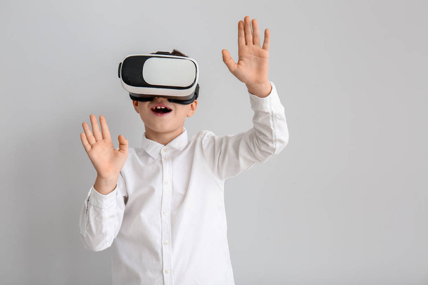 Little boy with virtual reality glasses on grey background - Photo, Image