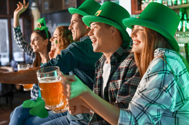Young friends celebrating St. Patrick's Day in pub - Foto, imagen