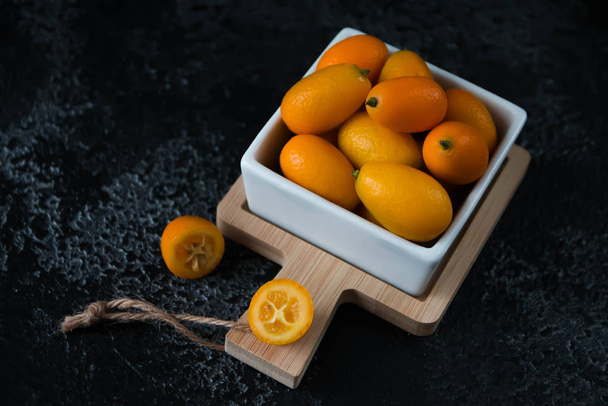 Cut fruit kumquat on a black background, citrus - Fotografie, Obrázek