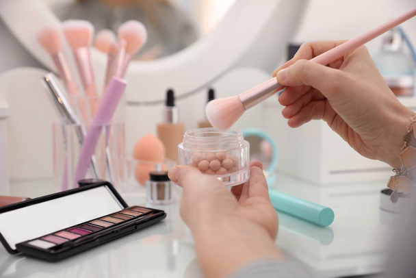 Woman applying makeup at dressing table, closeup - Фото, зображення