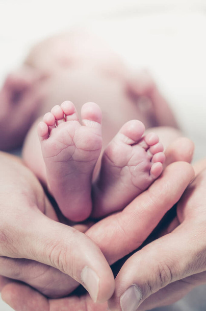 Feet of a newborn baby in the hands of parents. Happy family moment and concept. - Photo, Image