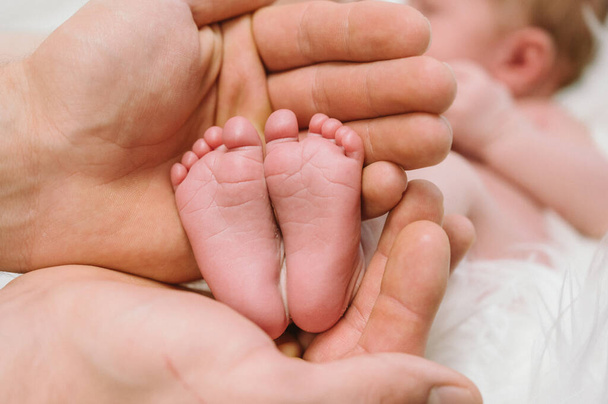 Egy újszülött lábai a szülők kezében. Boldog családi pillanatot és koncepciót. - Fotó, kép