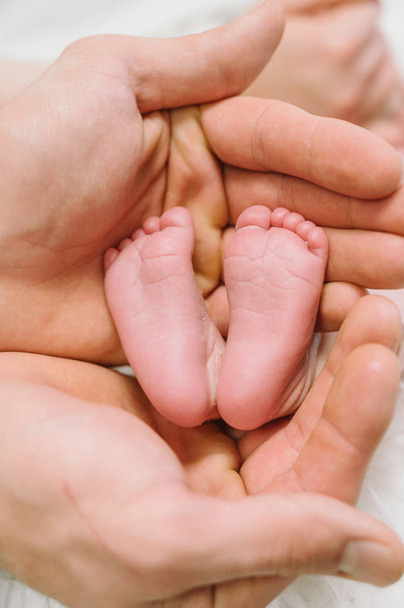 Feet of a newborn baby in the hands of parents. Happy family moment and concept. - Foto, afbeelding