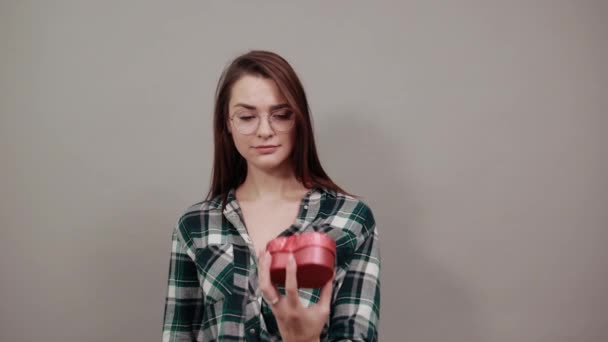 obrażona kobieta trzyma prezent czerwone pudełko w postaci serca, zatrzymuje się z dłoni - Materiał filmowy, wideo
