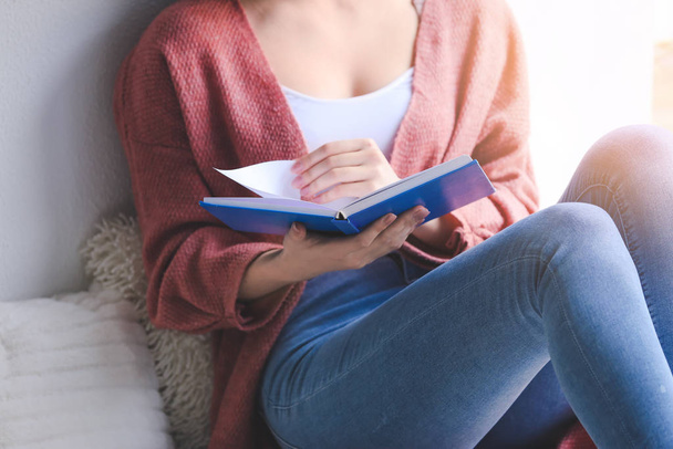 Evde kitap okuyan genç bir kadın, yakın çekim. - Fotoğraf, Görsel