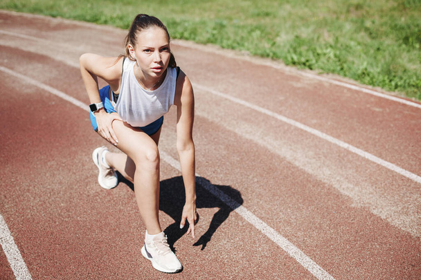 Young athlete prepares for a race at a sports stadium - Valokuva, kuva