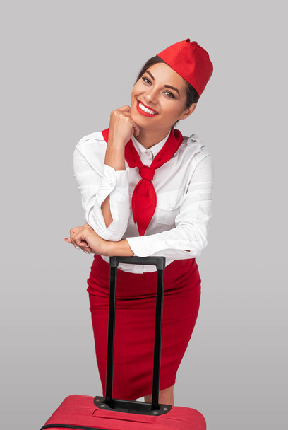 Happy ethnic flight attendant leaning on luggage - Valokuva, kuva