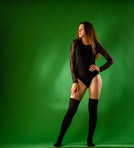 girl in black bodysuit on green background - Фото, зображення