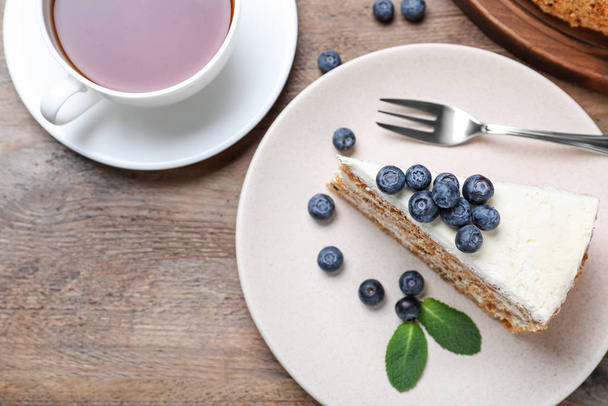 Tasty cake with berries and tea on wooden table, flat lay - Foto, imagen