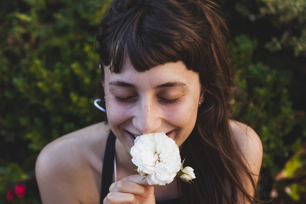 portrait of young cute woman is smelling a white flower - Foto, Imagen